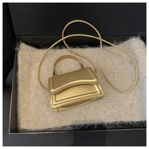 Close-up of a mini gold handbag in a luxury gift box with beige knit lining and thin strap