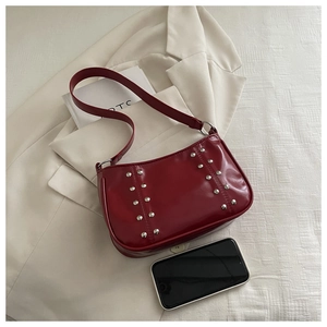 Close-up of burgundy leather crossbody bag with silver rivets and size reference