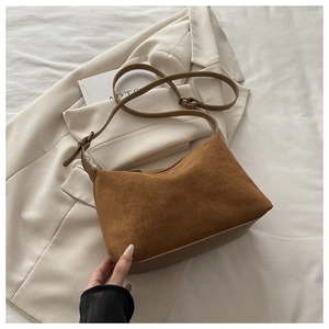 Detail of vintage brown suede shoulder bag with adjustable leather strap on white suit