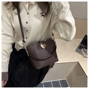 Détail d'un sac seau en cuir grainé marron foncé avec boucle métallique dorée en forme de cœur
