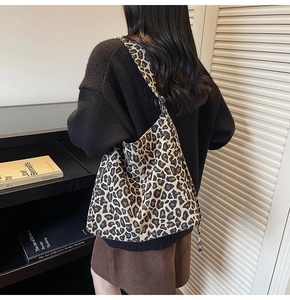 Detail of leopard print canvas tote bag featuring black fashion label and large capacity