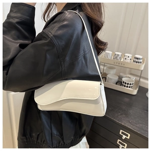 White glossy patent leather shoulder bag with asymmetrical flap shown on a model