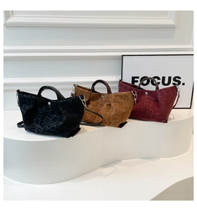 Detail view of leopard print faux suede handbags in black, brown, and burgundy colors