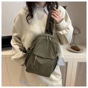 Detail of army green nylon crossbody bag showing the metal M logo and texture