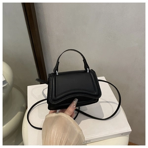 Detail of minimalist black crossbody bag with curved stitching and matte finish texture