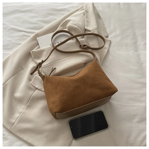 Detailed view of brown suede shoulder bag texture on white blazer background