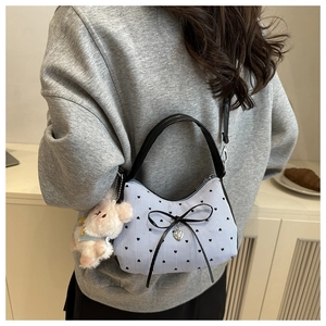 Sac à main à pois avec breloque lapin en peluche porté par un mannequin en sweat gris