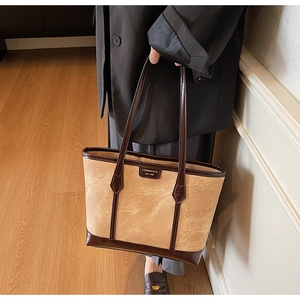 Détail d'un grand sac cabas en daim marron avec garniture en cuir et logo doré