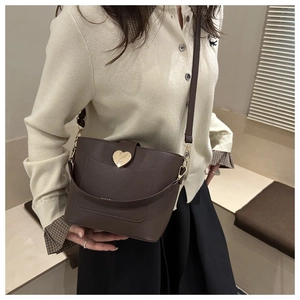 Détail du sac seau en cuir litchi marron foncé avec boucle en métal doré en forme de cœur