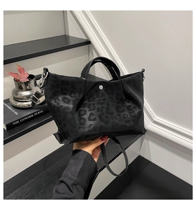 Detailed close-up of black leopard pattern tote bag with metal hooks and shoulder strap