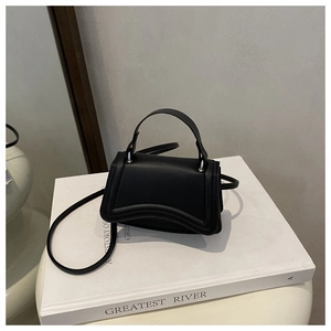 Detail of black matte trapezoid handbag with signature curved base and thin crossbody strap