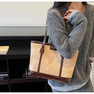 Détail d'un sac cabas beige minimaliste avec garniture en cuir marron foncé