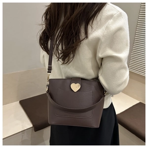 Détail du sac seau en cuir marron foncé avec une boucle en métal doré en forme de coeur
