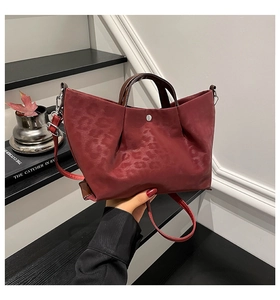 Detail of dark red leopard embossed leather tote bag with silver magnetic snap closure