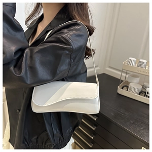 Detail of white glossy patent leather shoulder bag with wavy edge design and slim strap