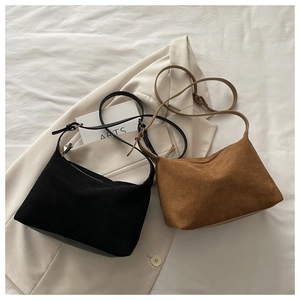 Detailed flat lay of matte suede crescent bags in black and caramel with slim straps