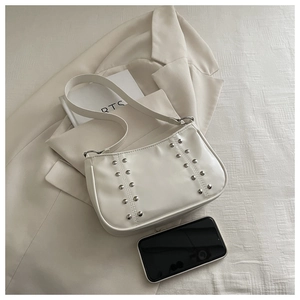 Detail shot of white leather crossbody bag with silver rivets and minimalist shoulder strap