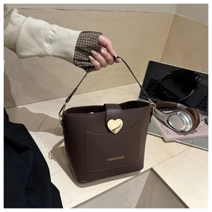 Vue détaillée du sac seau marron avec fermoir cœur doré et texture cuir grainé