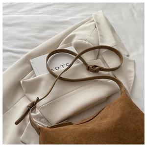 Close-up of brown suede crescent hobo bag with adjustable strap and zipper detail