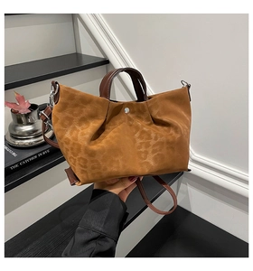 Detail of leopard print embossed tote with brown leather handles and magnetic closure