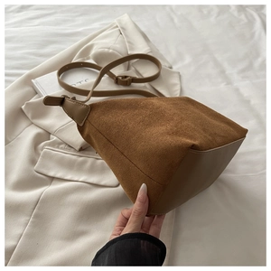 Detail of brown suede shoulder bag showing matte texture and reinforced stitched leather base