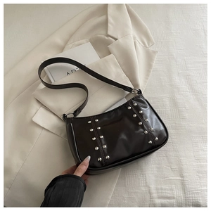 Detail of vintage square crossbody bag with silver studs on dark glossy faux leather