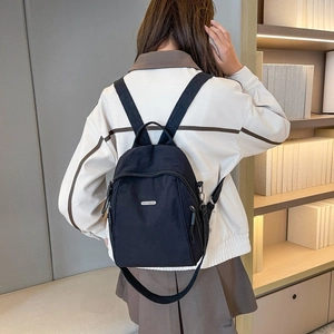 Nahaufnahme eines modischen schwarzen Nylonrucksacks, getragen von einem Modell im Innenraum