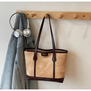 Détail d'un sac cabas kaki avec garniture en cuir marron et étiquette de marque vintage