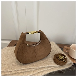 Gros plan sur le daim marron du sac hobo avec détails dorés sur un support en tricot
