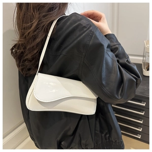 Close-up of a white patent leather baguette bag with an asymmetrical wave flap design