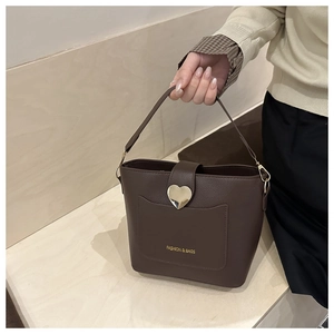 Détail du sac seau marron foncé avec texture litchi et boucle en cœur dorée