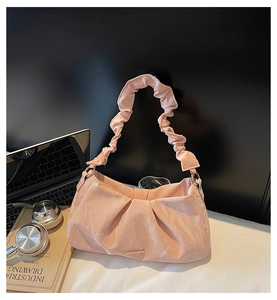 Dettaglio della borsa a nuvola rosa con trama in seta a pieghe e accenti in metallo oro