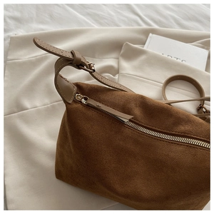 Detail of dark brown suede shoulder bag featuring a smooth metal zipper and fine stitching