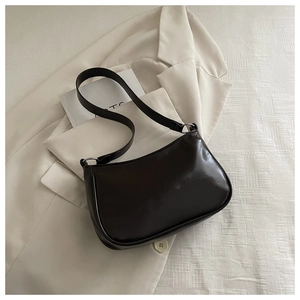 Detail of dark brown retro shoulder bag with smooth texture on beige suit background