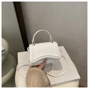 Detail of white mini crossbody bag with textured lines and curved top handle