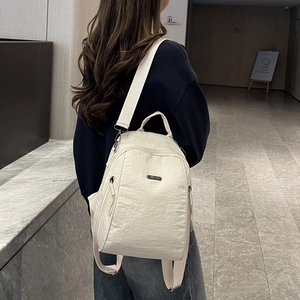 Detailansicht eines cremefarbenen Nylon-Rucksacks mit Faltenstruktur und Trageriemen