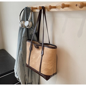 Détail du grand sac cabas vintage avec bordures en similicuir sur un crochet mural