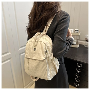 Detail view of off-white minimalist nylon backpack with multiple pockets and side water bottle holder