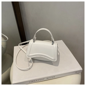 Detailed view of white mini handbag with curved flap on a decorative display stand