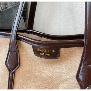 Gros plan du sac en toile beige avec étiquette en cuir marron et lettrage doré chic