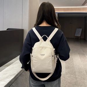 Model trägt einen großen cremefarbenen Nylon-Rucksack, Rückansicht mit stilvollen Trägern