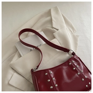 Close-up of a retro burgundy tote bag with silver studs on a stylish white blazer