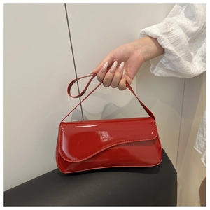 Close-up of a glossy red patent leather handbag with adjustable shoulder strap