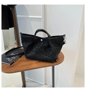 Detail view of the black leopard pattern faux suede tote bag with silver metal buckles