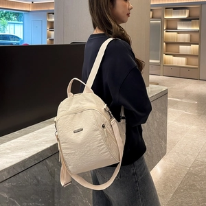 Detailansicht des cremefarbenen Nylonrucksacks mit Metalllogo und Reißverschlussdetails