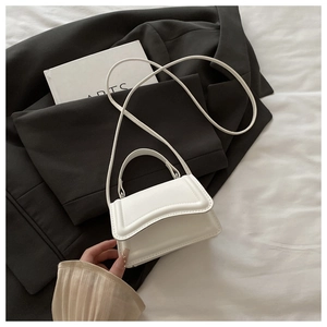 Detail of white leather mini handbag with top handle and slim shoulder strap