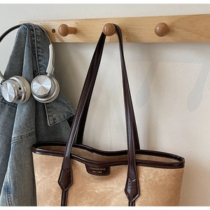 Gros plan d'un sac cabas vintage beige avec poignées en cuir marron sur crochet bois