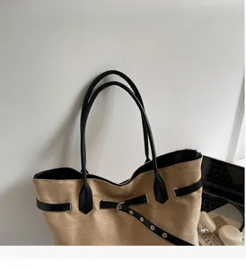 Detail der khakifarbenen Wildleder-Tasche mit schwarzen Lederriemen und Metallschnalle