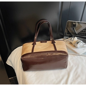 Détail d'un sac cabas bicolore vintage avec texture plissée et logo embossé élégant