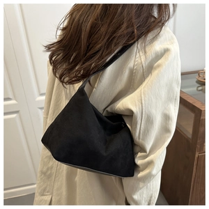 Close-up of minimalist black matte suede tote bag styled with a beige trench coat